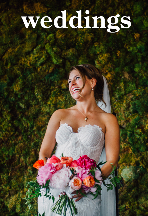bride laughing holding bouquet of peonies in front of moss covered wall