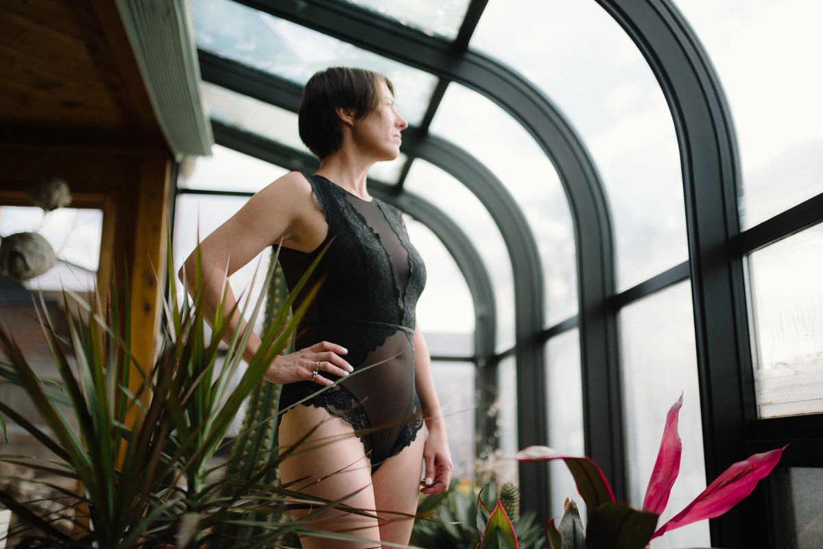 woman looking through sunroom window in black lingerie