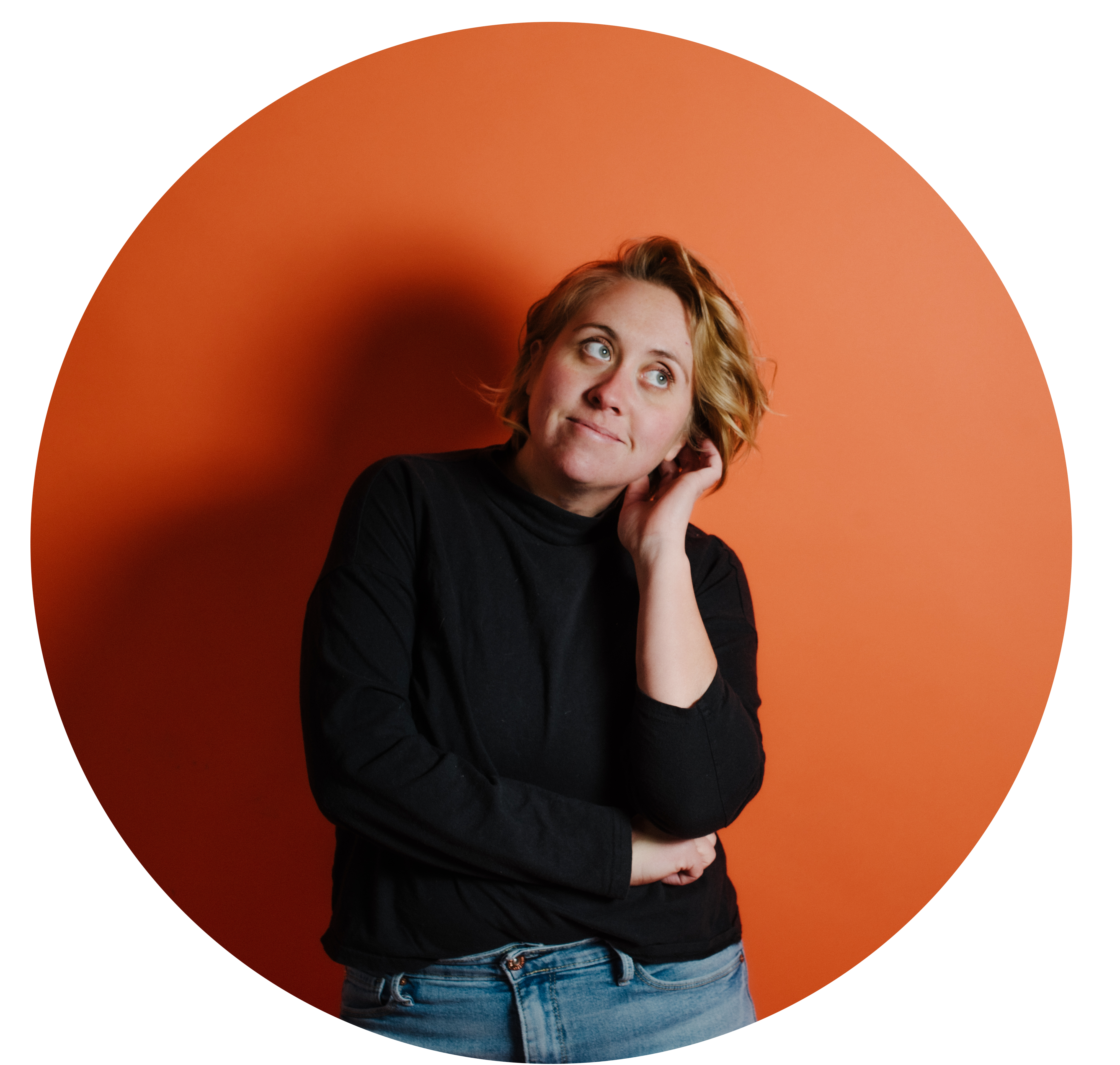 photo of the photographer with short blonde hair wearing a black turtleneck and blue jeans on orange backdrop leaning her head on her left hand looking up