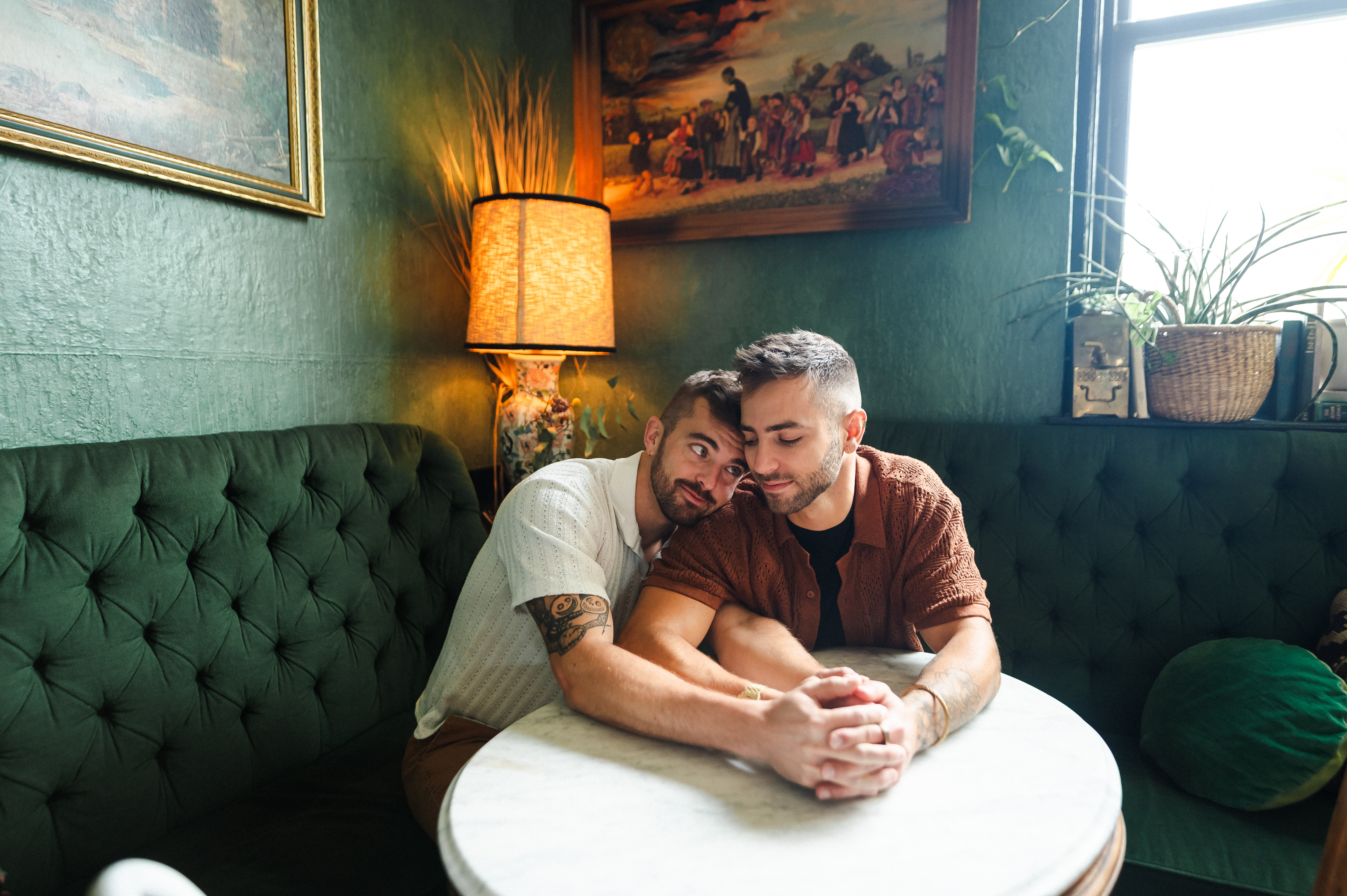 Frank and Blake sit at a table holding hands